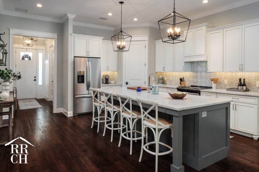 Custom Home Build Longleaf Kitchen with Hallway to Entrance with Large Eat-In Island and Modern Industrial Light Fixtures | Robinson Renovation & Custom Homes, Inc.