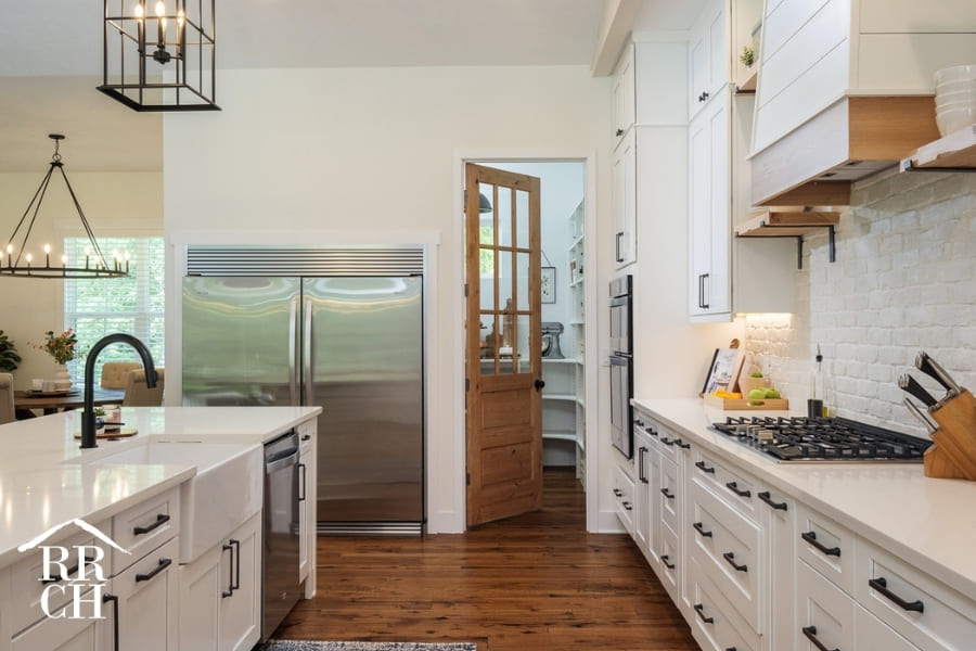 Custom Home Build Modern Farmhouse Kitchen Area Doorway into Private Pantry - Dylans Grove 2 | Robinson Renovation & Custom Homes, Inc.