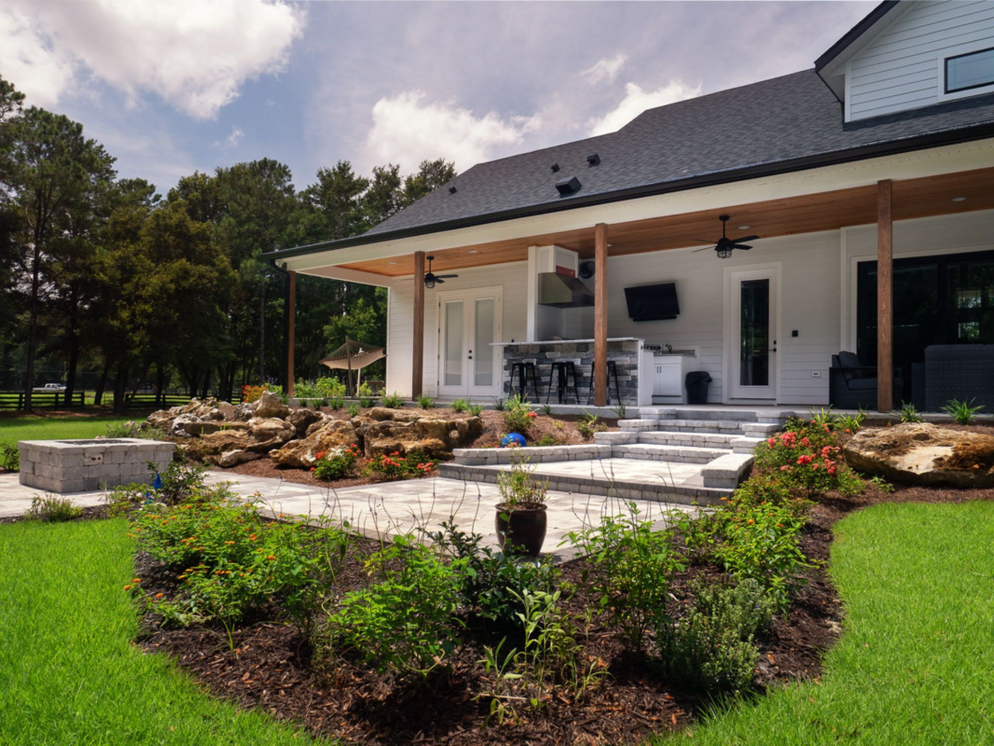Outdoor living space in Gainesville, FL with an outdoor kitchen, lounge area, and landscaping by Robinson Renovation & Custom Homes